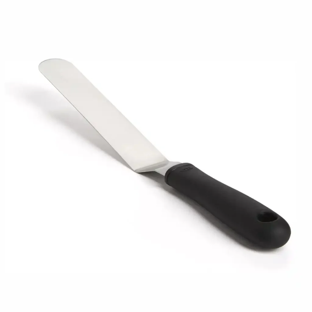 Offset spatula spreading chocolate ganache on cupcake